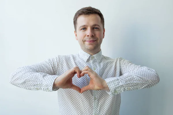 Joven hombre caucásico haciendo de las manos corazón. Hacer obras de caridad, cuidar de la salud o estar enamorado — Foto de Stock