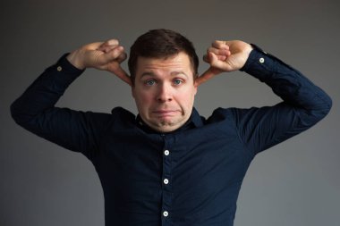 Beyaz adam kulakları işaret parmağı ile kapatır. 