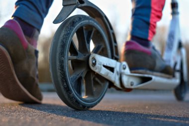 Büyük tekerlekleri ile uygun şehir scooter. Bir kız spor ayakkabı içinde gitmek hazırlanıyor.