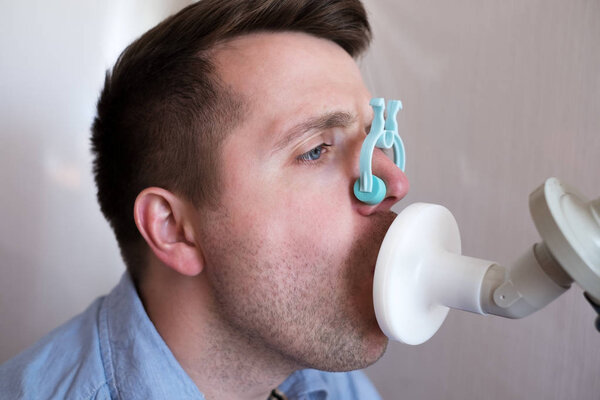 Молодой человек проверяет функции дыхания по спирометрии
.