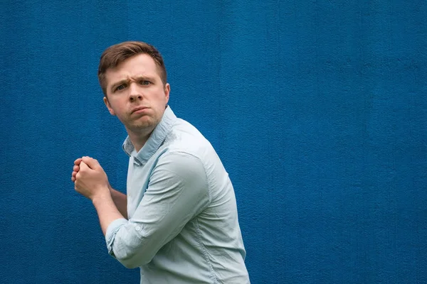 Genç açgözlü biri bir şey elinde gizler ve caddenin ileri görünüyor.