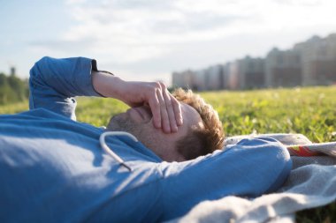 Üzgün yorgun adam uzanmış silah ile yeşil çim üzerinde yalan.