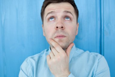 Mavi woodenwall tarafından ayakta beyaz düşünceli genç adam.