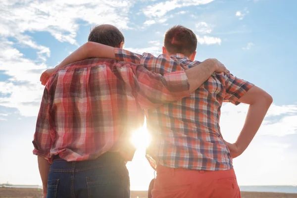 Padre e hijo adultos tomados de la mano al atardecer — Foto de Stock