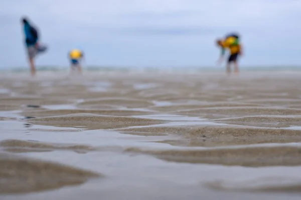 Морський піщаний пляж з розмитими силуетами людей — стокове фото