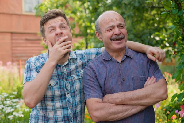 To gjespende slitne menn på fylkets side på solskinnsdag – stockfoto