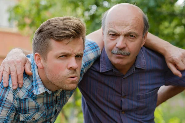 Portrait of doubting men. Dad and son look forward and frown — Stock Photo, Image