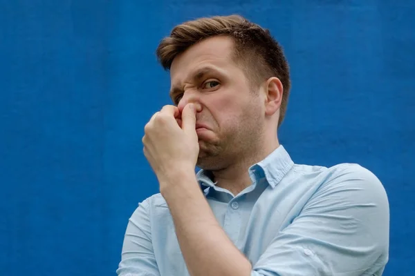 Retrato de un joven caucásico cerrando la nariz debido al terrible olor — Foto de Stock