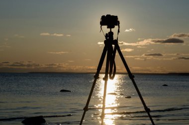 Fotoğraf makinesi tripod üzerinde sunset yakınında deniz suyu ile