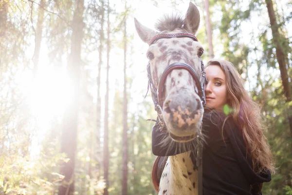 Jovem caucasiana cuidando de seu cavalo, abraçando seu pescoço . — Fotografia de Stock