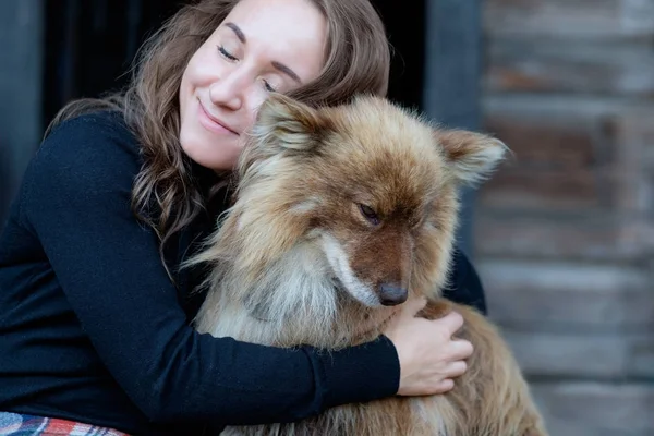 Uma mulher bonita e seu cão nenets pastor laika sentado . — Fotografia de Stock