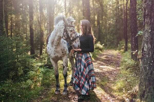 Jovem caucasiana cuidando de seu cavalo, andando na floresta . — Fotografia de Stock