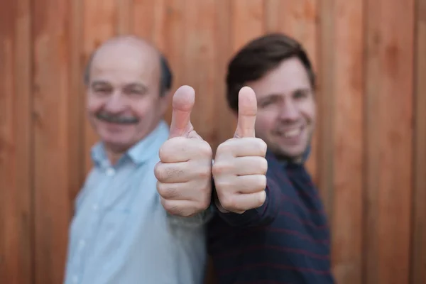 Twee gelukkige mannen geven duimen omhoog teken. Onscherpe foto. — Stockfoto