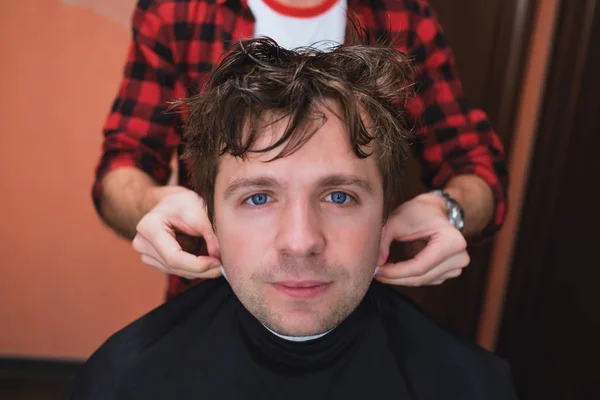 The hairdresser puts on a protective blanket on the client.