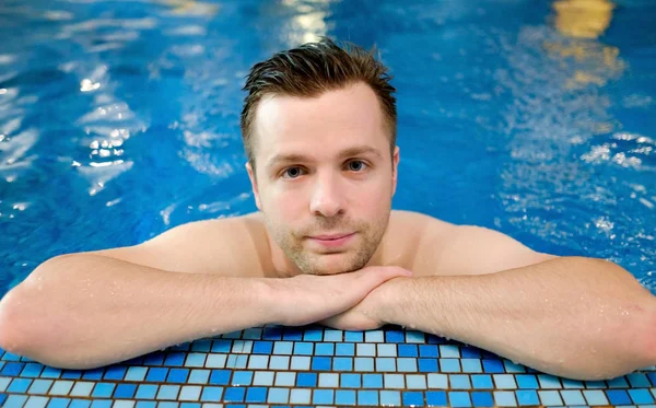 Quell'uomo sta riposando sul bordo della piscina. Mani vicino al mento . — Foto Stock