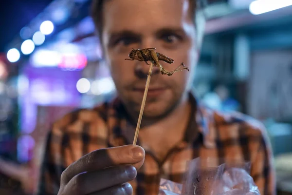 Kaukasische junge Männer essen Cricket auf dem Nachtmarkt in Thailand. — Stockfoto