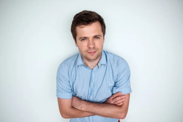 Confident young caucasian handsome man in blue shirt keeping arms crossed and smiling — Stock Photo, Image