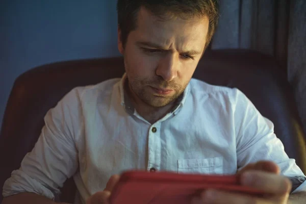 Молодий кавказький чоловік на портативному комп'ютері зі світловим відображенням від екрану до обличчя, що працює вдома . — стокове фото