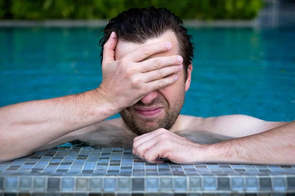 Een jonge man in het zwembad veegt zijn gezicht met zijn hand. — Stockfoto