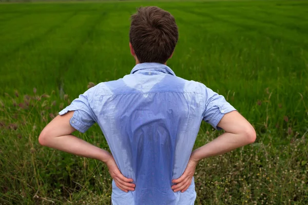 Uomo con iperidrosi che suda molto male sotto l'ascella in camicia blu, isolato su grigio — Foto Stock