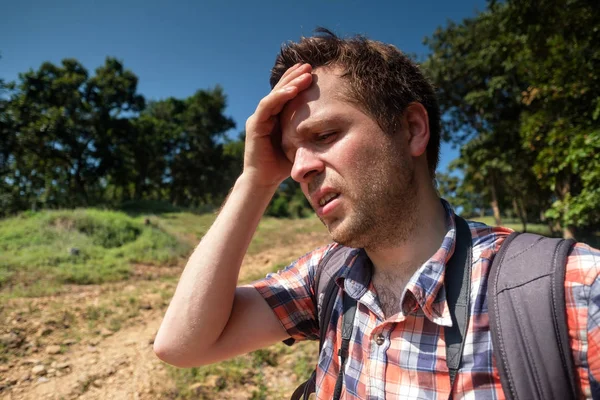 Hombre cansado en el bosque unfder sol fuerte con mochila. Viaja solo en Asia. Sufrir insolación — Foto de Stock