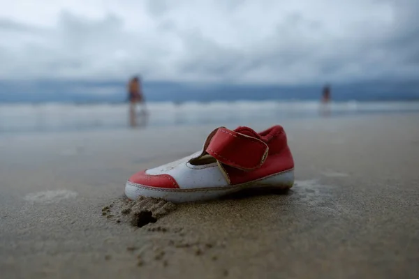 Втрачено дитяче взуття на піску пляжу — стокове фото