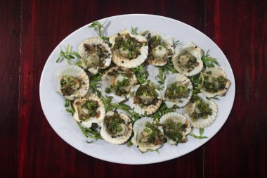 Limon, kişniş ve ahşap masa üzerinde beyaz plaka üzerinde beyaz şarap ile ızgara tarak.