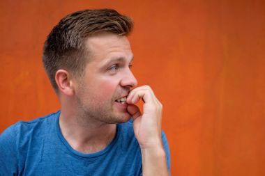 Tırnaklarını kemiren kırmızı zemin üzerine beyaz olgun adam.