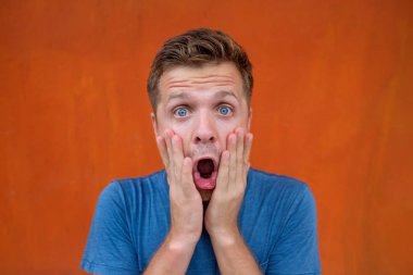 Yakışıklı beyaz adam iyi haberle şok mı? O kırmızı duvara yakın duruyor