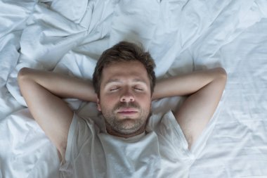 Beyaz adam mutlu yüz ifadesiyle uyuklayan.