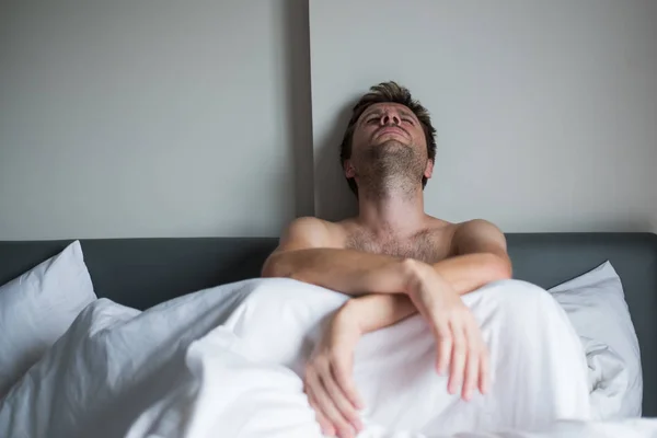 Портрет засмученого молодого чоловіка, який сидить на самоті на ліжку . — стокове фото