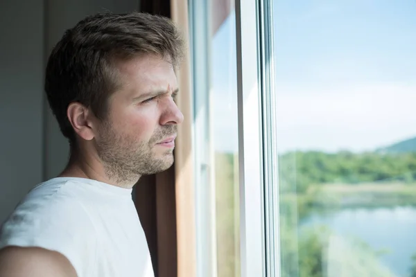 Ung man stående vid fönstret i morgon. Han står upp tidigt — Stockfoto