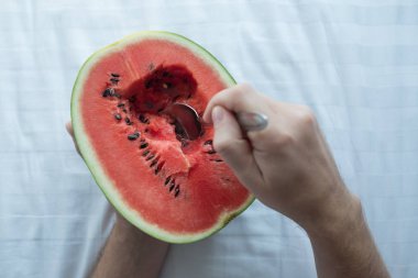 Genç adam bir karpuz evde kaşıkla yemek