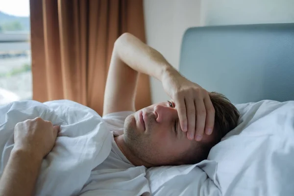 Hombre acostado en la cama en casa sufriendo de dolor de cabeza o resaca — Foto de Stock