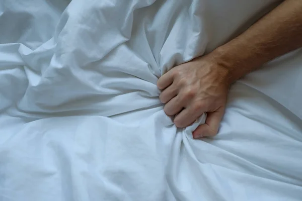 Кавказский мужчина держит руку на кровати — стоковое фото