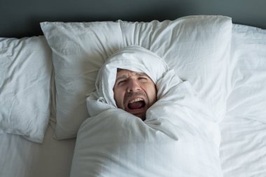 Beyaz adam beyaz battaniye ile haddelenmiş.