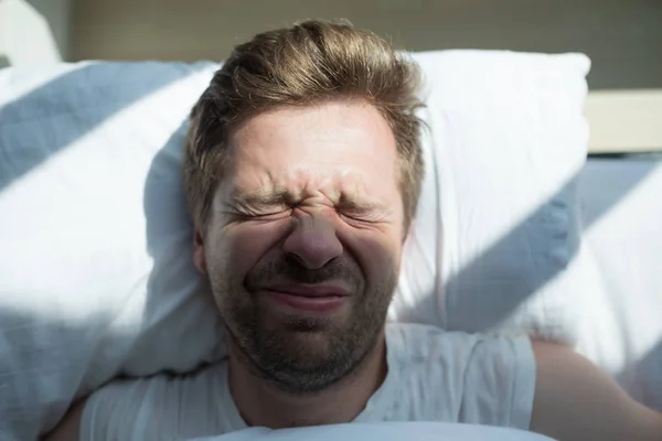 Kaukasische volwassen man in het witte t-shirt wil niet opstaan in de ochtend — Stockfoto