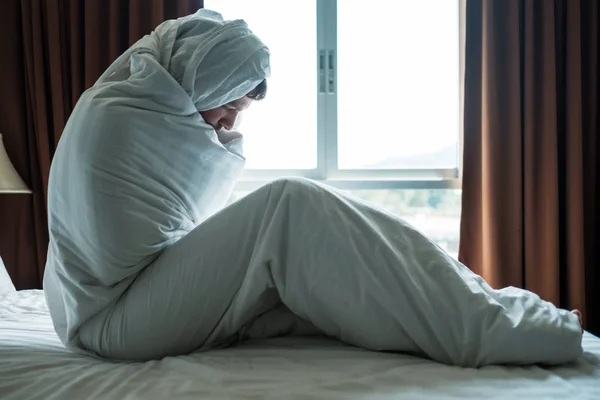 Pria tertekan yang duduk di tempat tidurnya tertutup selimut dan melihat ke jendela. Dia depresi setelah bercerai. — Stok Foto