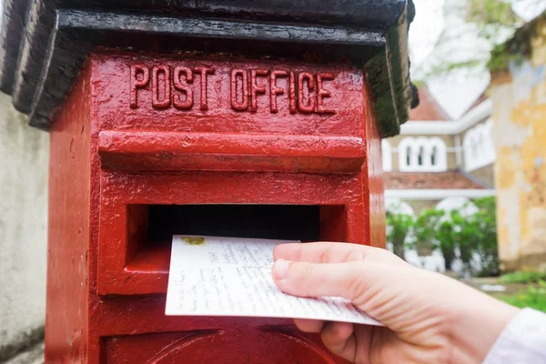 Feche-se em uma mão masculina pondo uma carta em uma caixa de correio vermelha. Conceito de tipo vintage de comunicação . — Fotografia de Stock