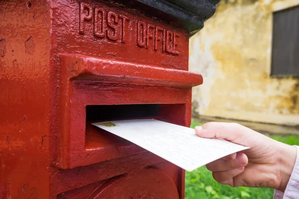 Close-up op een mannenhand zetten een brief in een rode brievenbus. Concept van vintage type communicatie. — Stockfoto