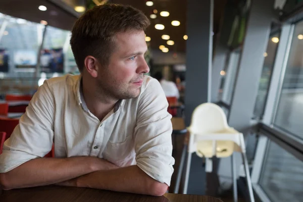 Caucásico hombre sentado solo en la cafetería y mirando a un lado . — Foto de Stock