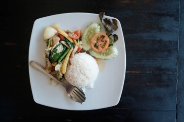 ahşap masa üzerinde duran beyaz tabak kırmızı sebzeli pilav