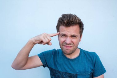 Mavi arka plan üzerinde bir çözüm bulmaya Tapınağı üzerinde parmak tutan bir şey hakkında düşünme genç adam