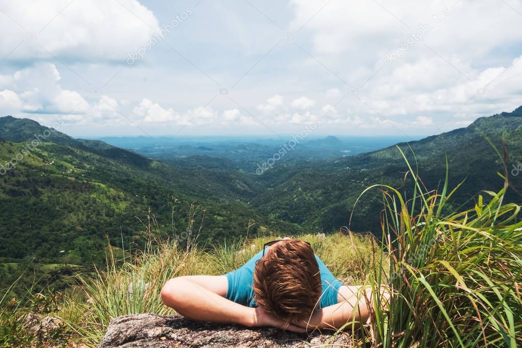 Man lying on grass and looking on beautiful mountain view in Sri lanka