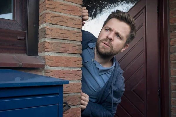 Joven guapo abriendo la puerta mirando lo que su vecino está haciendo . —  Fotos de Stock