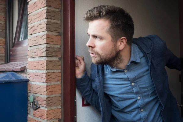 Flot ung mand, der åbner døren og kigger på, hvad hans nabo laver . - Stock-foto