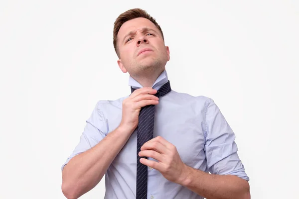 Confused young business man trying to make a knot on his tie. — Stock Photo, Image