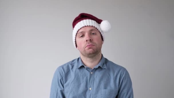 Young sad man takes off his santa claus hat. Holidays are over. — Stock Video