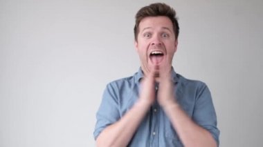 Genç beyaz adam el çırpıyor, haberlerle heyecanlanıyor.