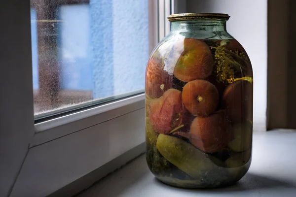 Un frasco de vidrio de tomates enlatados cerca de la ventana en casa . — Foto de Stock